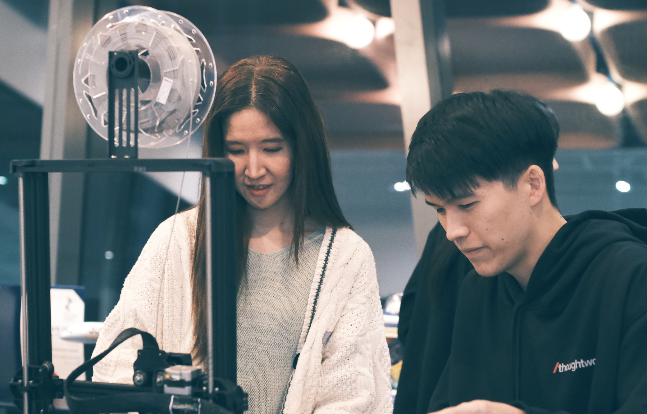 Two Thoughtworkers looking at a machine in an office. Two Thoughtworkers looking at a machine in an office.